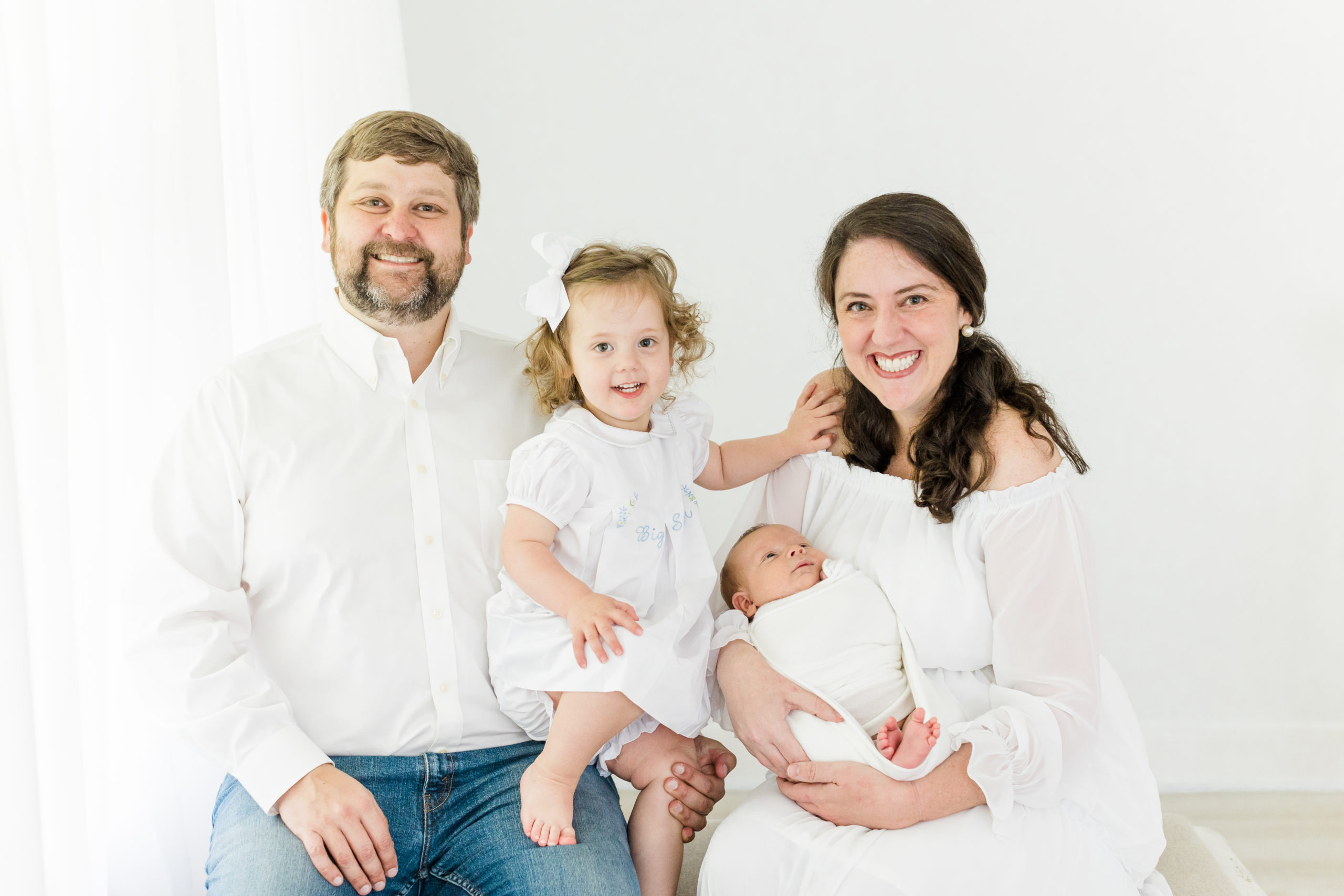 Posed in front of a natural light window in her photography studio, Houston, Texas photographer, Monette Anne Photography captures this family of four during their newborn photoshoot. newborn baby boy white swaddle white studio houston texas white color scheme family photos #HoustonTexasFamilyPhotographer #HoustonTexasNewbornPhotographer #HoustonTexasPhotographyStudio #MontroseTexasNewbornPhotographer #MontroseTexasFamilyPhotographer #MuseumDistrictTexasPhotographer #MuseumDistrictFamilyPhotographer #FamilyPhotoOutfits #StudioNewbornPhotos #MonetteAnnePhotography