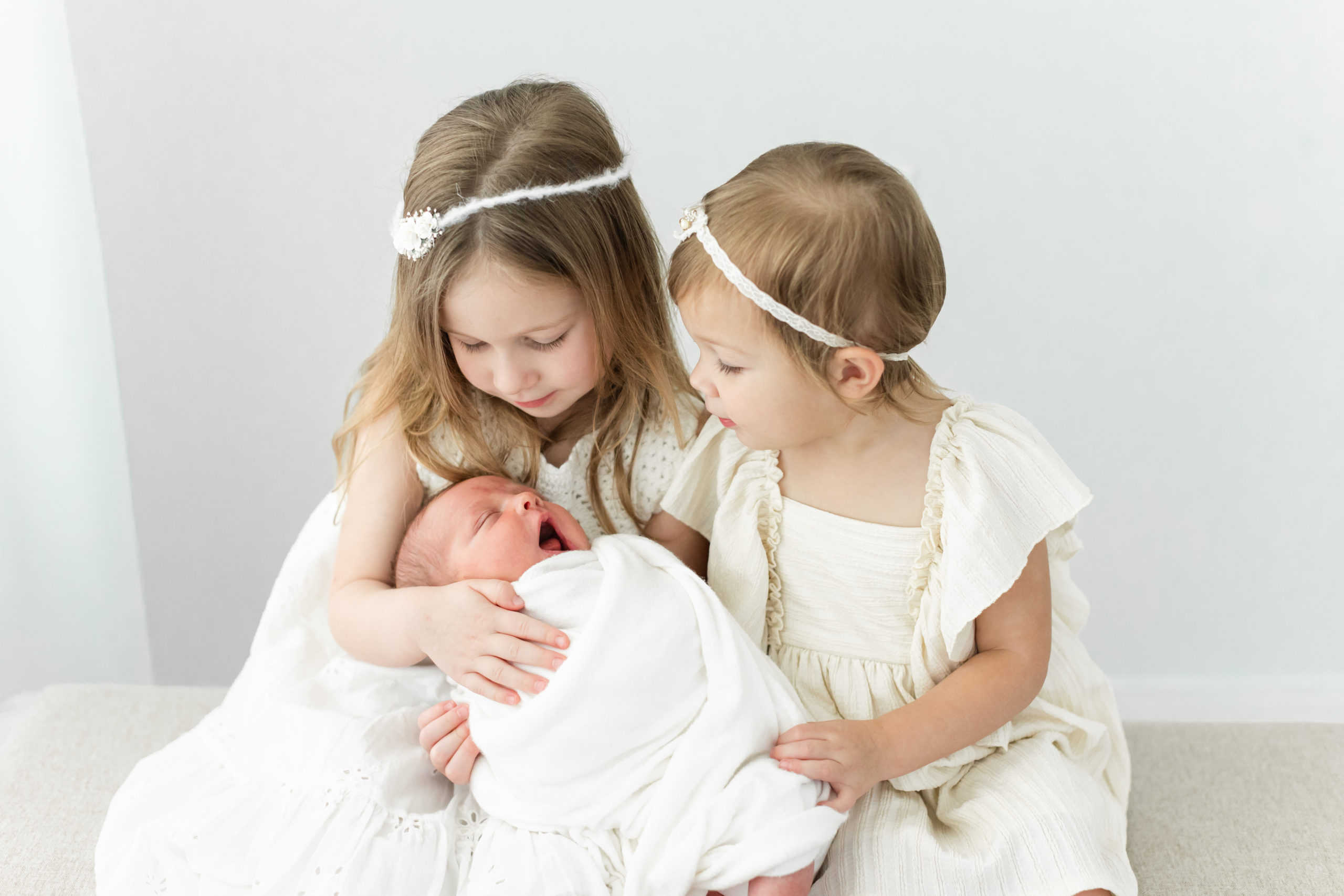 Monette Anne Photography captures two sweet older sisters loving on their brand new baby brother in a clean antique studio in Houston, Texas. sibling photo little brothers #monetteannephotography #monetteannenewbornphotography #monetteannefamilyphotography #houstonfamilyphotographer #houstonnewbornphotographer #familyoffive #babybrother #siblingpictures #oldersisters #threekids #photographywardrobe #montrossestudio